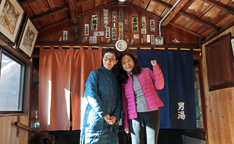 温泉 鹿の湯の入り口で記念撮影をする編集者とそめおりさんの写真